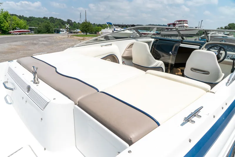 Slide: The Image of 2001 Cobalt 227 Cuddy boat interior with white seating and dashboard, parked outdoors. - 10