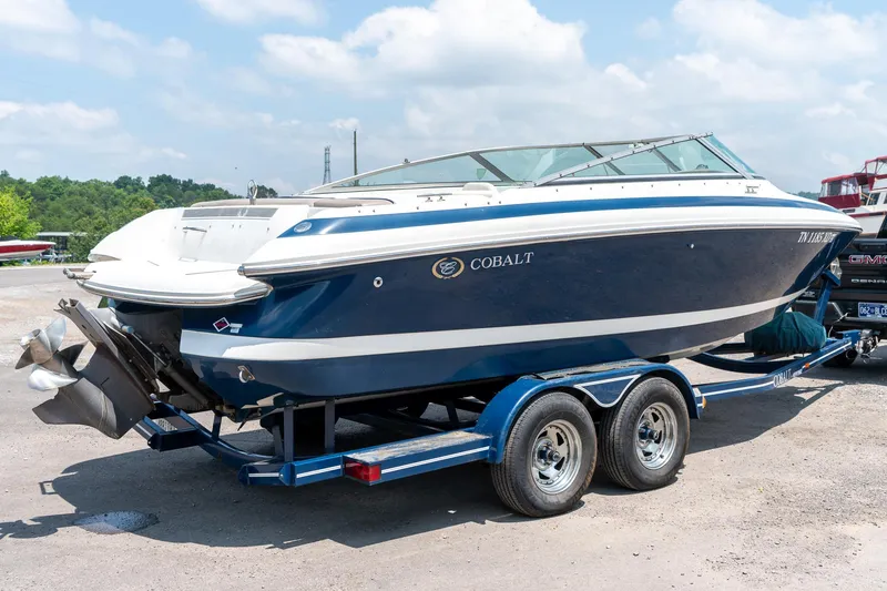 Slide: The Image of 2001 Cobalt 227 Cuddy boat on trailer, blue and white design, parked outdoors. - 3