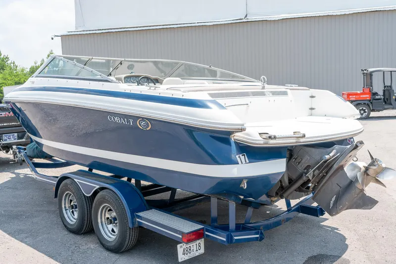 Slide: The Image of 2001 Cobalt 227 Cuddy boat on trailer, blue and white design, parked outdoors. - 6