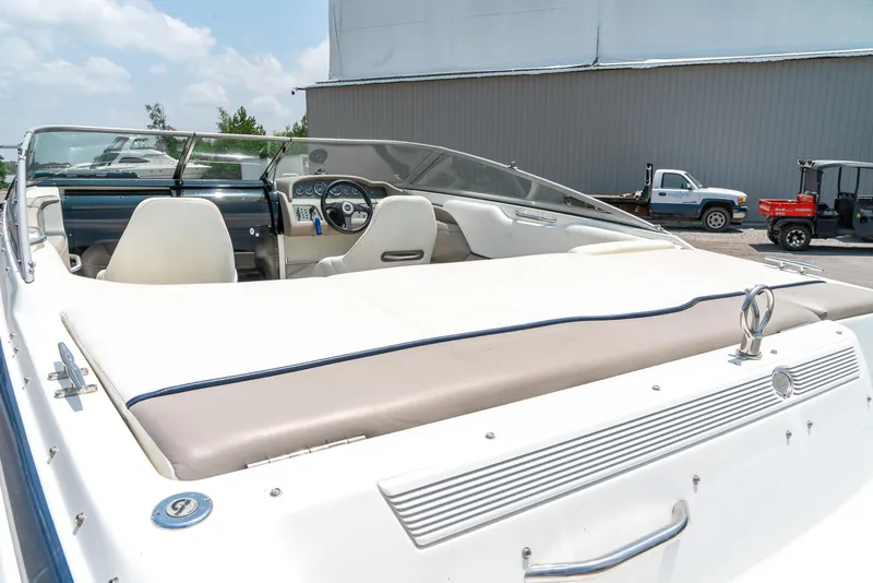 Slide: The Image of 2001 Cobalt 227 Cuddy boat interior with steering wheel and seating, parked outdoors. - 8