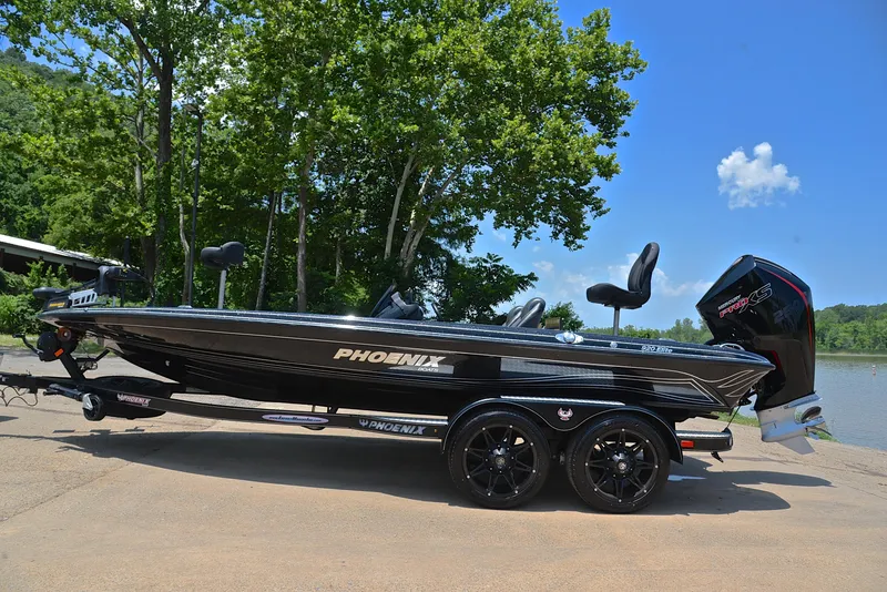 Slide: The Image of 2022 Phoenix 920 Elite boat on trailer, parked by a lake with trees in the background. - 12