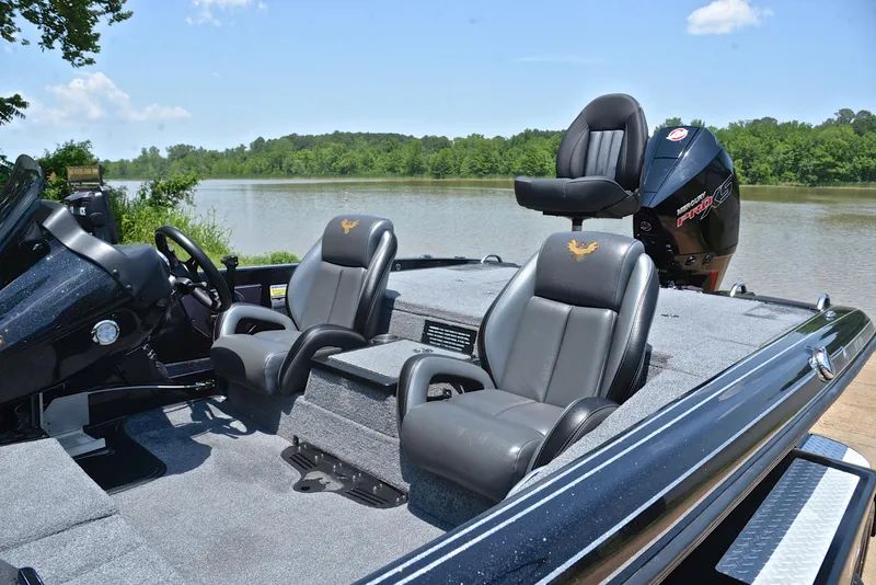 Slide: The Image of 2022 Phoenix 920 Elite boat interior with seating, steering, and motor by a scenic river. - 19
