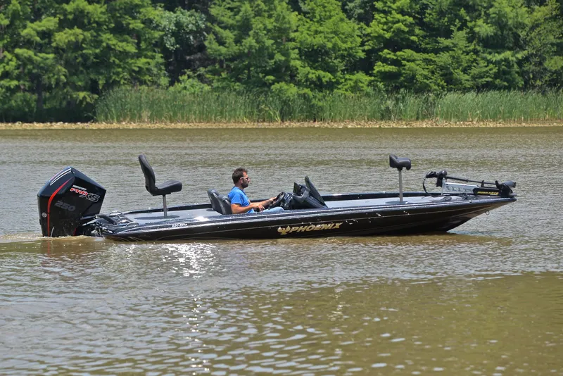 Slide: The Image of 2022 Phoenix 920 Elite boat cruising on a calm river with lush green trees. - 7