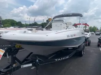 Slide: The Image of 2023 Tahoe 2150 Deck Boat CC on trailer, parked outdoors under cloudy sky. - 1