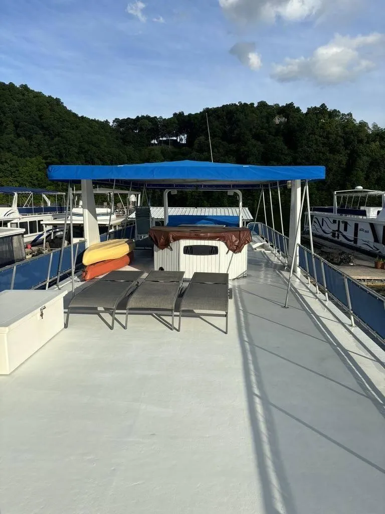 Slide: The Image of 1998 Stardust Cruisers 16x77 houseboat with sun deck, loungers, and canopy on a serene lake. - 13