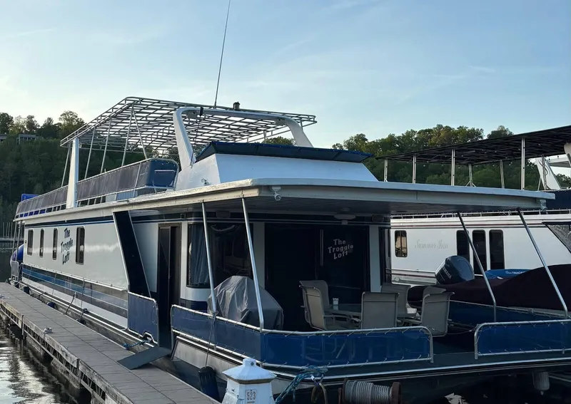 Slide: The Image of 1998 Stardust Cruisers 16x77 houseboat docked, featuring spacious deck and outdoor seating. - 2