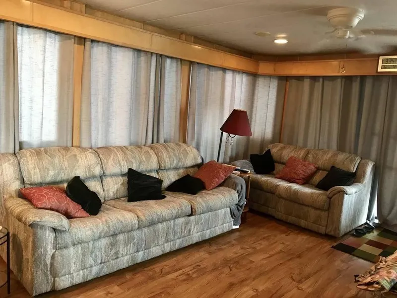 Slide: The Image of 1998 Stardust Cruisers 16x77 houseboat interior with sofas, cushions, and wooden flooring. - 9