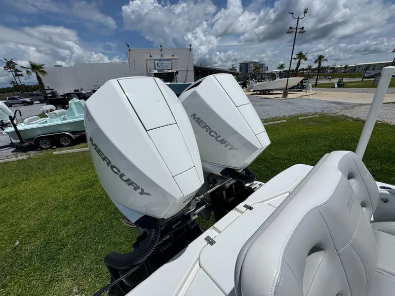 Slide: The Image of Twin Mercury outboard engines on a 2021 ZCB 26 Freemason boat, parked on grass. - 34
