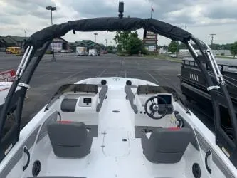 Slide: The Image of 2024 Tahoe T21 boat interior with dual seating and steering console in a parking lot. - 4