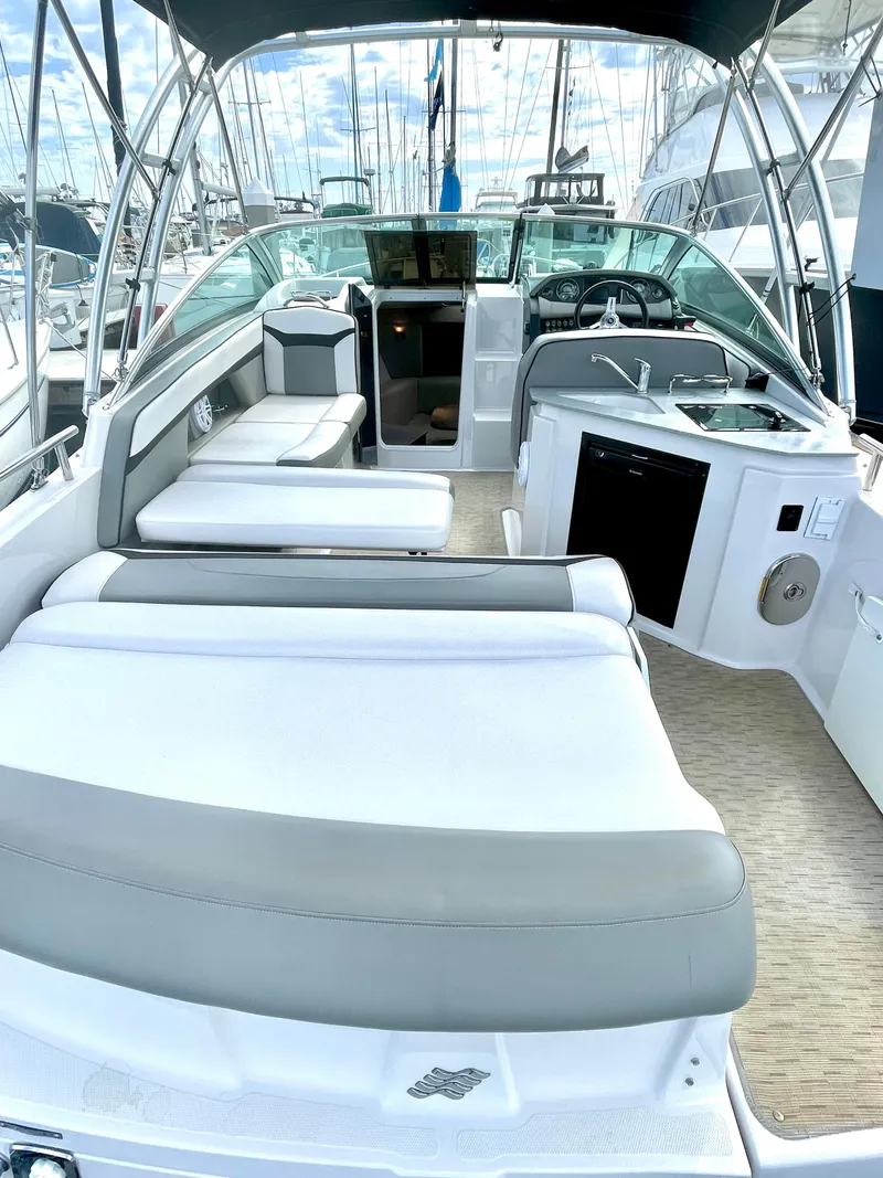 Slide: The Image of 2016 Four Winns 255 Vista boat interior with seating, kitchenette, and helm, docked at marina. - 2