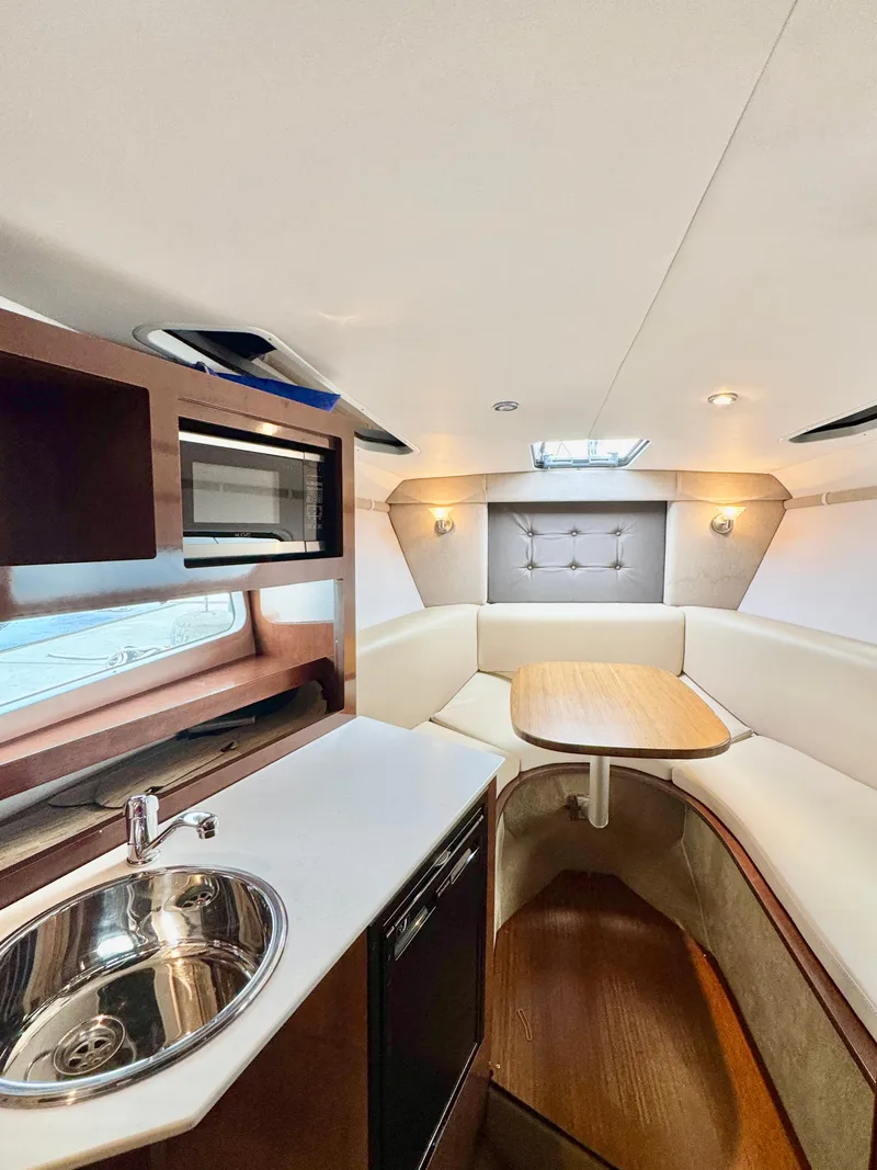 Slide: The Image of 2016 Four Winns 255 Vista cabin interior with kitchenette, seating, and table. - 5