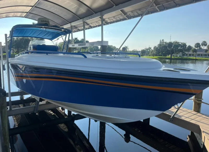Slide: The Image of 2011 Spectre 360 Roadster boat docked under a canopy, featuring a sleek blue and white design. - 2