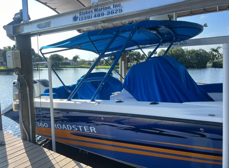 Slide: The Image of 2011 Spectre 360 Roadster boat docked with blue cover and canopy, scenic waterfront view. - 3