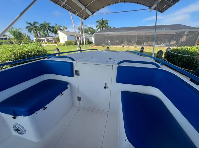 Slide: The Image of Spectre 360 Roadster 2011 boat interior with blue seating and canopy, surrounded by lush greenery. - 4