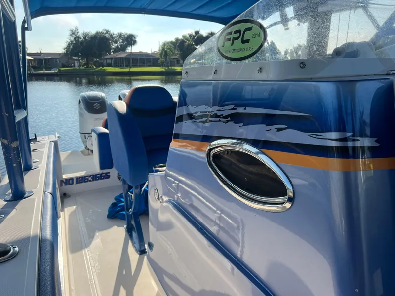 Slide: The Image of Spectre 360 Roadster 2011 boat interior with blue seating, docked by a serene lake. - 41