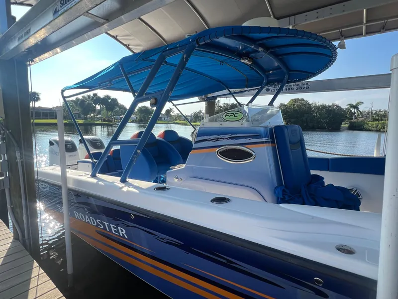 Slide: The Image of 2011 Spectre 360 Roadster boat docked, featuring blue and white design with canopy. - 42