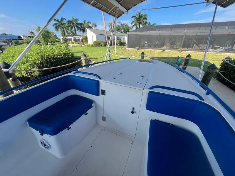 Slide: The Image of Spectre 360 Roadster 2011 boat interior with blue seating, docked near lush greenery. - 46