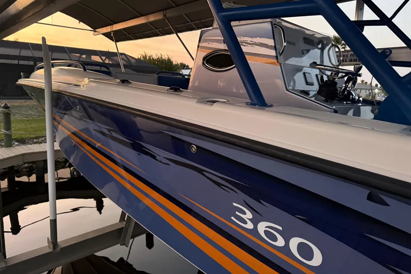 Slide: The Image of 2011 Spectre 360 Roadster boat with sleek blue and orange design at sunset. - 59