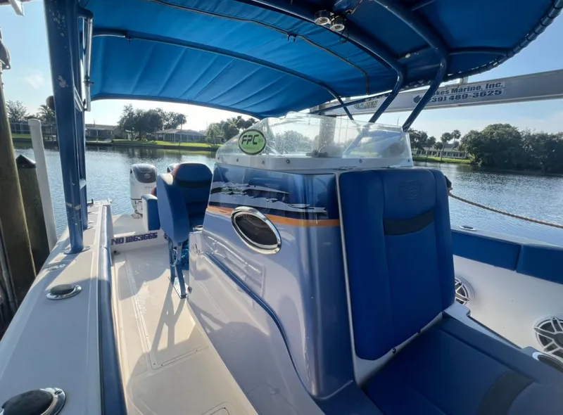 Slide: The Image of 2011 Spectre 360 Roadster boat with blue interior and canopy, docked by a serene waterfront. - 6