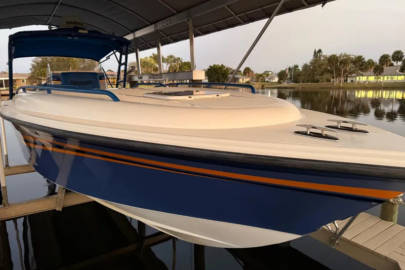 Slide: The Image of 2011 Spectre 360 Roadster boat docked under a canopy, featuring sleek blue and orange design. - 60