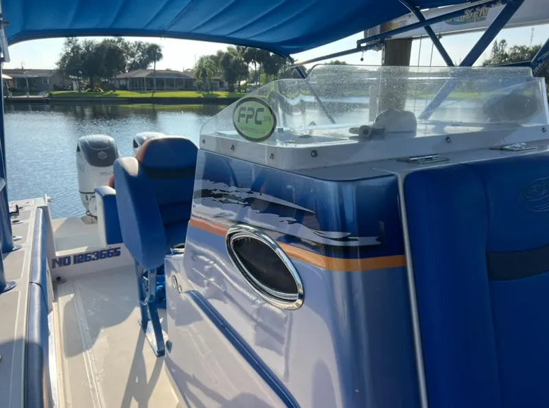 Slide: The Image of 2011 Spectre 360 Roadster boat interior with blue seating and console, docked by a serene lake. - 7