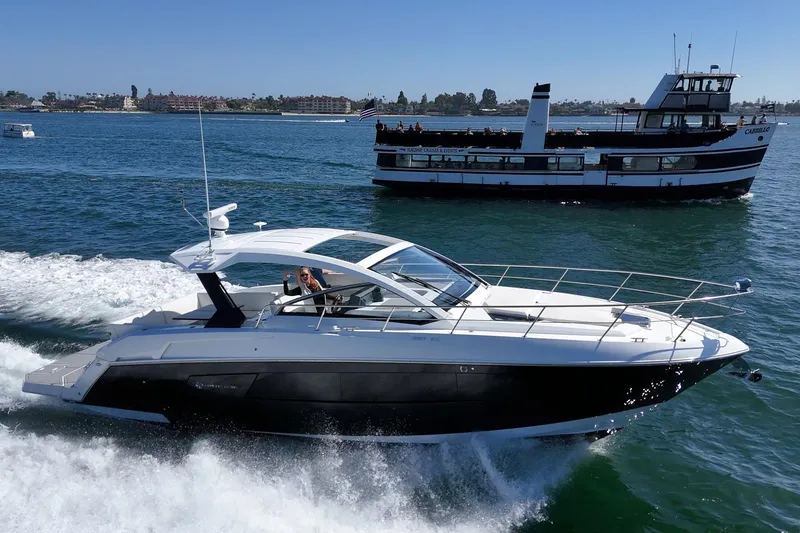 Slide: The Image of 2021 Cruisers Yachts 390 Express Coupe cruising on open water, with a ferry in the background. - 1