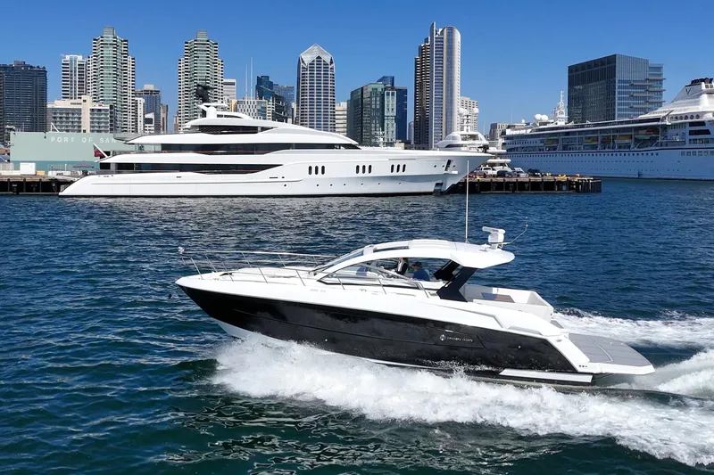 Slide: The Image of 2021 Cruisers Yachts 390 Express Coupe cruising in urban harbor with skyscrapers in background. - 2