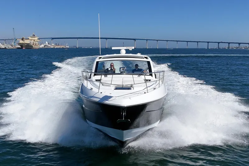 Slide: The Image of 2021 Cruisers Yachts 390 Express Coupe speeding on open water with bridge in background. - 21