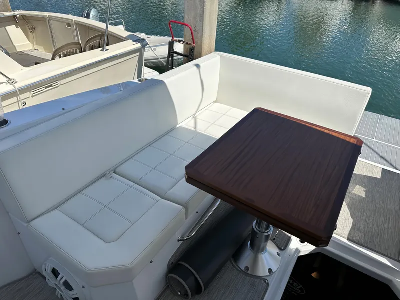 Slide: The Image of 2021 Cruisers Yachts 390 Express Coupe, white seating, wooden table, docked by water. - 41
