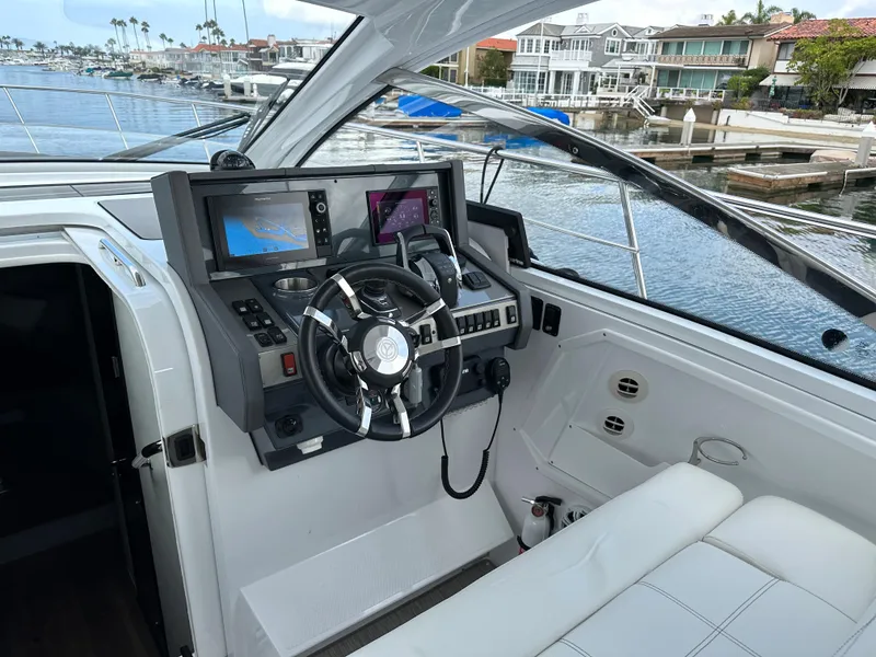 Slide: The Image of 2021 Cruisers Yachts 390 Express Coupe helm with modern controls and waterfront view. - 46