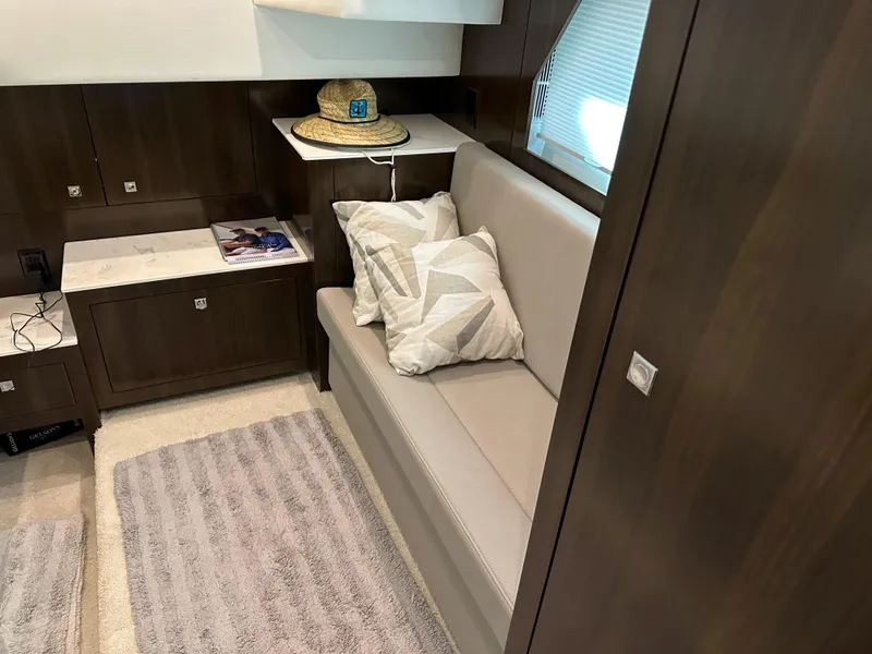 Slide: The Image of Interior of 2021 Cruisers Yachts 390 Express Coupe with sofa, pillows, and wooden cabinetry. - 51