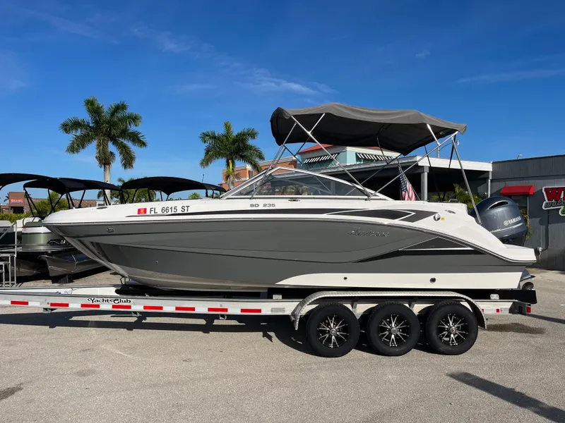 Slide: The Image of 2020 Hurricane SunDeck 235 OB boat on trailer, parked outdoors under clear blue sky. - 7