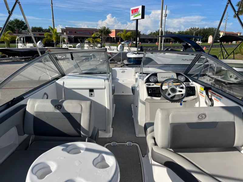 Slide: The Image of 2020 Hurricane SunDeck 235 OB boat interior with seating and steering wheel, parked outdoors. - 9