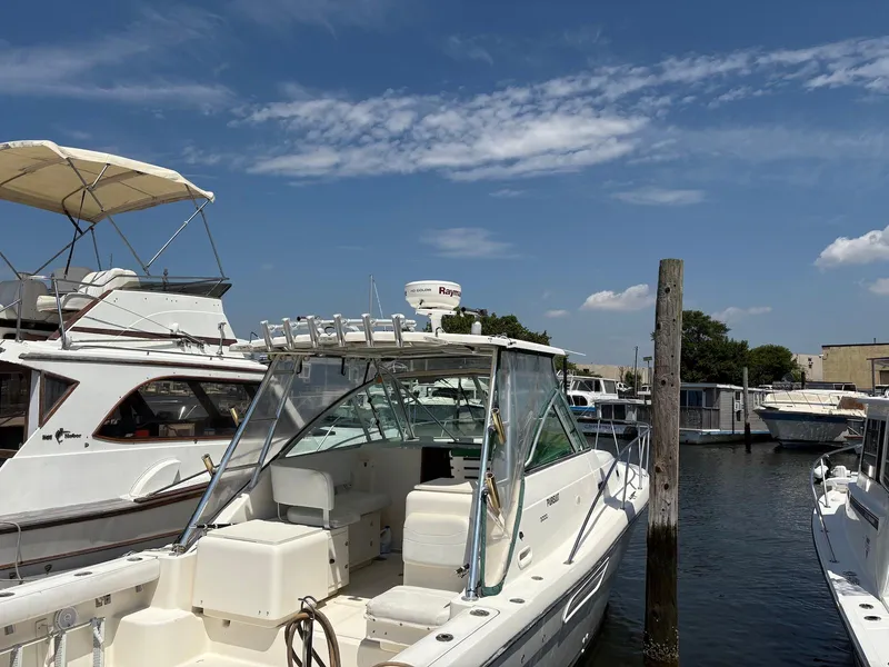 The Image of 2002 Pursuit 3000 Express boat docked at marina under clear blue sky. - 0