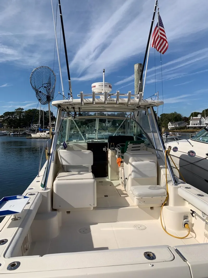 Slide: The Image of 2002 Pursuit 3000 Express boat docked, featuring spacious deck and American flag. - 2