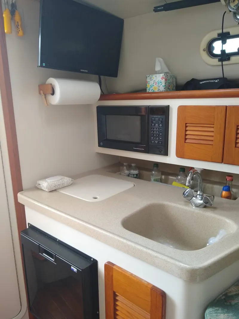 Slide: The Image of 2002 Pursuit 3000 Express boat kitchen with sink, microwave, and TV. - 21