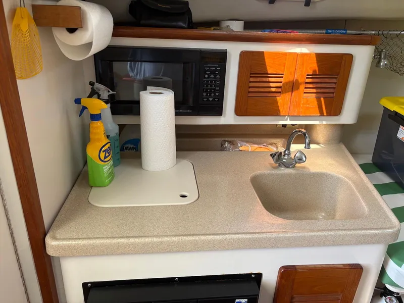 Slide: The Image of Compact kitchen area in a 2002 Pursuit 3000 Express boat with sink and storage. - 25