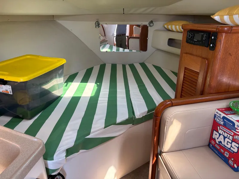 Slide: The Image of Interior of 2002 Pursuit 3000 Express boat with striped bedding and storage items. - 26