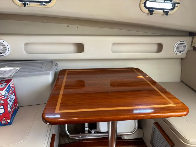 Slide: The Image of 2002 Pursuit 3000 Express cabin with wooden table, storage, and seating. - 27
