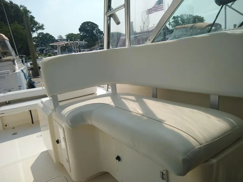 Slide: The Image of 2002 Pursuit 3000 Express boat interior with white seating in a marina setting. - 6