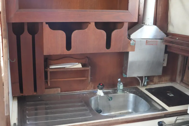 Slide: The Image of 1977 Fisher 37 MS yacht kitchen with wooden cabinetry and stainless steel sink. - 24