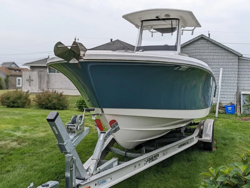 Slide: The Image of 2021 Edgewater 262 CC boat on trailer, parked on grass near houses. - 3