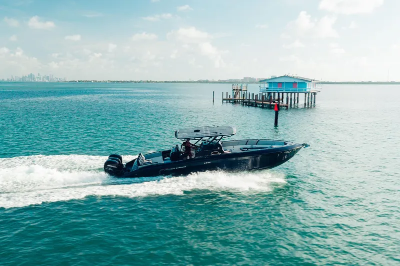 The Image of 2014 Midnight Express 37’ Open boat cruising near a stilt house on a sunny day. - 0