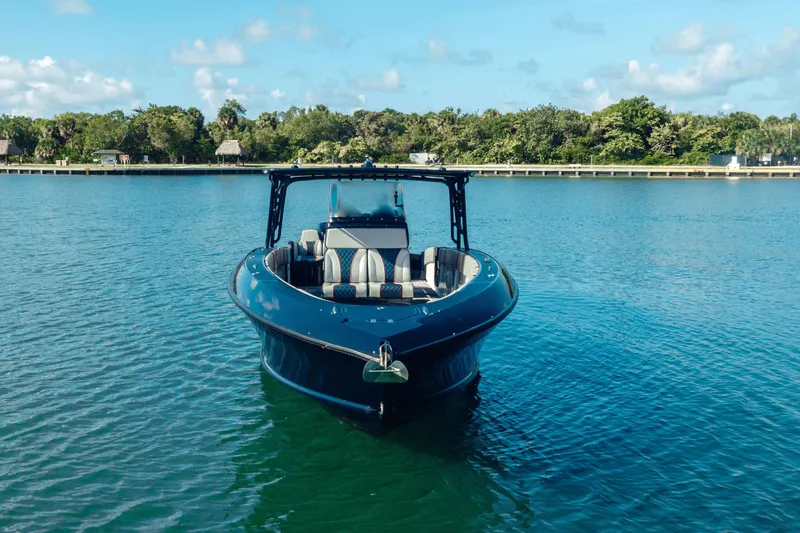 Slide: The Image of 2014 Midnight Express 37’ Open boat on calm water with lush green shoreline. - 14