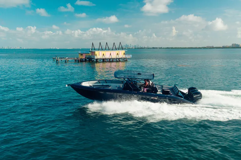 Slide: The Image of 2014 Midnight Express 37’ Open boat cruising on blue ocean near a colorful dock. - 8