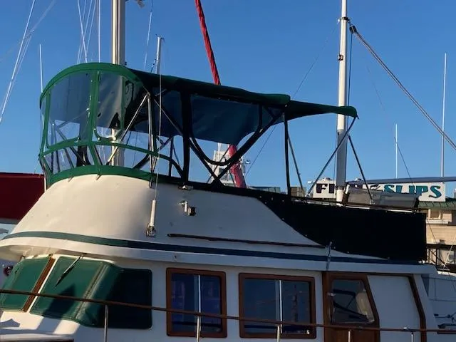 Slide: The Image of 1986 Albin 36 Trawler with green canopy, docked at marina under clear blue sky. - 5