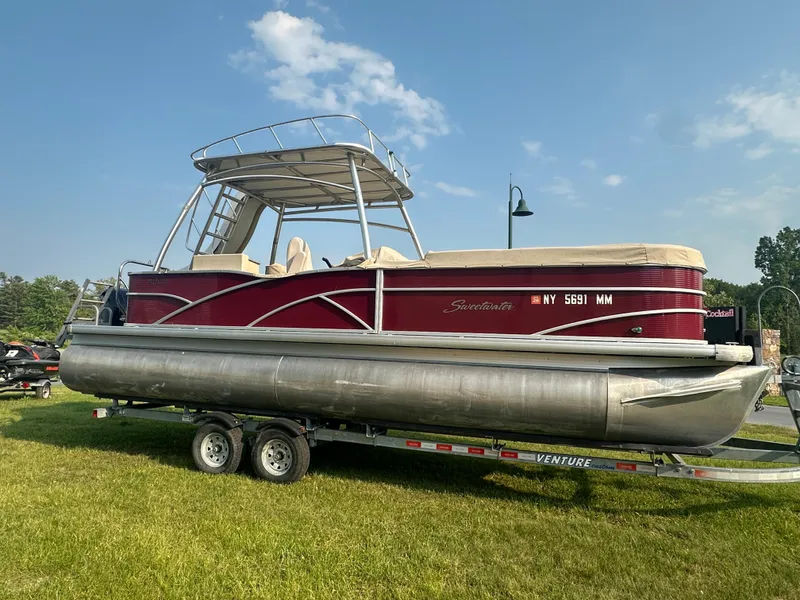 The Image of 2017 Godfrey Sweetwater 2386 CC pontoon boat on trailer, parked on grass. - 1