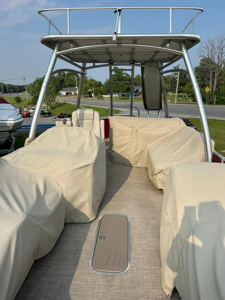 Slide: The Image of 2017 Godfrey Sweetwater 2386 CC boat with covered seating and canopy, parked outdoors. - 16