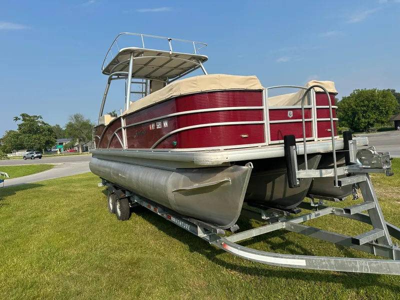 Slide: The Image of 2017 Godfrey Sweetwater 2386 CC pontoon boat on trailer, parked on grass. - 5