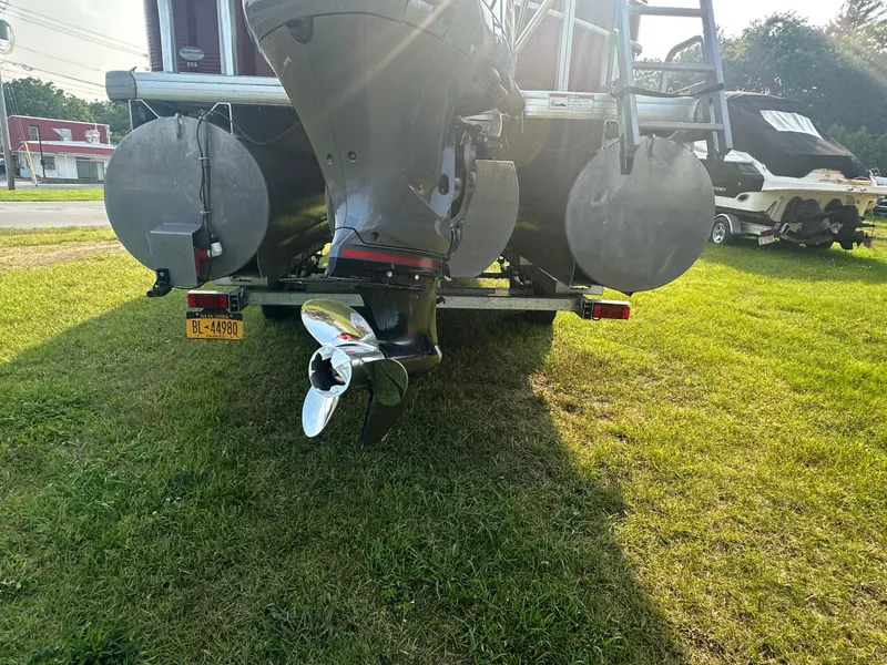 Slide: The Image of 2017 Godfrey Sweetwater 2386 CC boat on grass, rear view with visible outboard motor. - 6